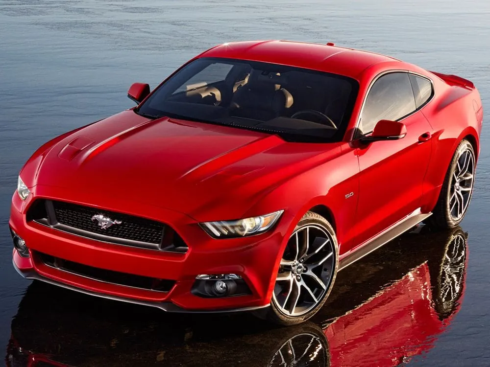 Close-up of a glossy black car door panel with masking tape, showing precise preparation for professional car detailing.